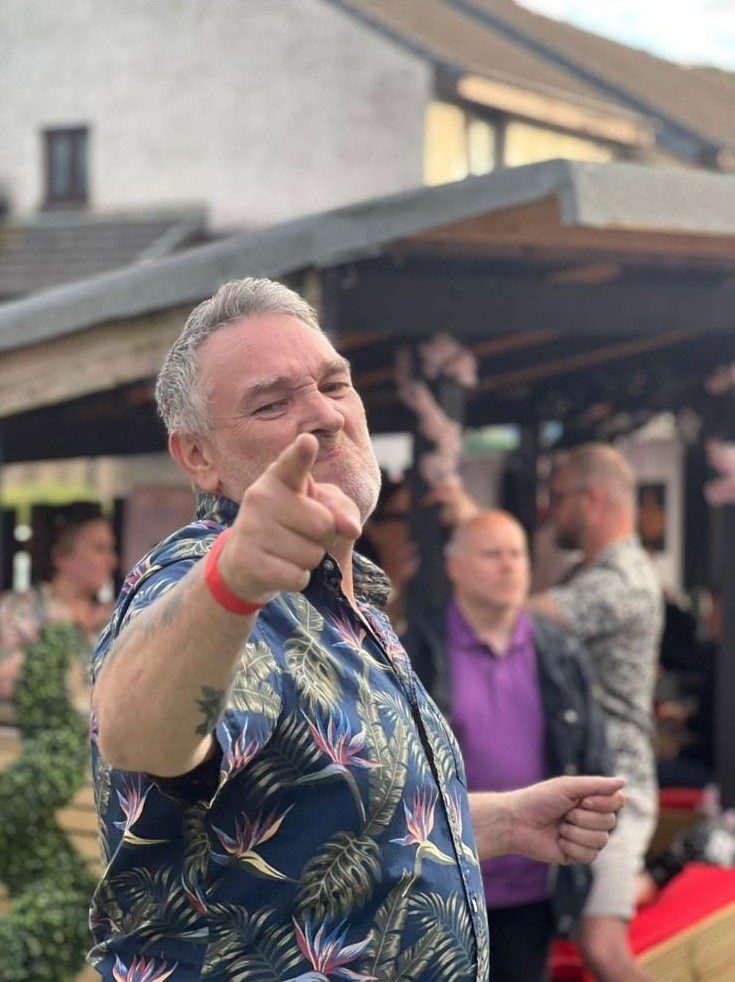 A man in a floral shirt cheering with the Social Legacy crew at a gathering