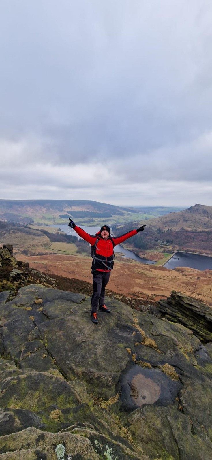 A walker with arms outstretched on a mountain summit